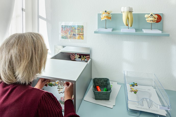 Eine Frau übt mit einem Puzzle das spiegelverkehrte Arbeiten an einer Mitmachstation im Zahnarztbereich der Villa Medica. Foto: Jannis Wiebusch