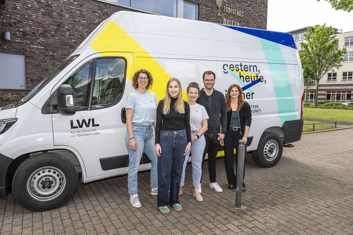 Das Projektteam steht mit Mitarbeiterinnen des Jüdischen Museums Westfalen vor dem "Gedenkstättensprinter".