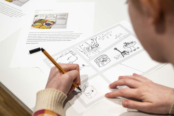 Eine Frau arbeitet an einem Tisch mit einem Stift an Fortbildungsmaterialien. Foto: Thorsten Arendt