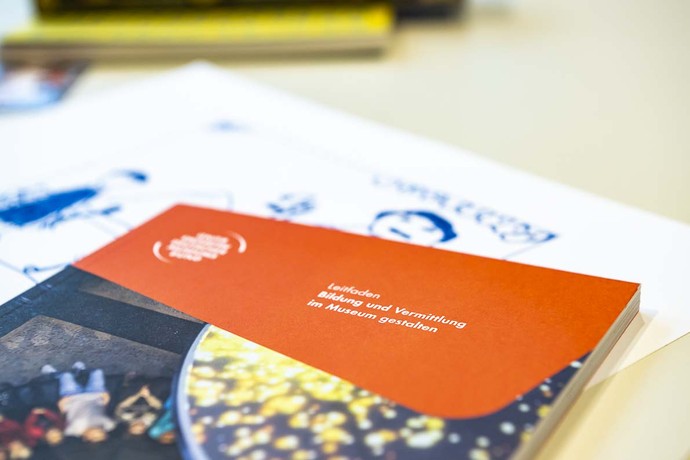 Das Buch "Leitfaden. Bildung und Vermittlung im Museum gestalten" und ein Zettel liegen auf einem Tisch. Foto: Thorsten Arendt