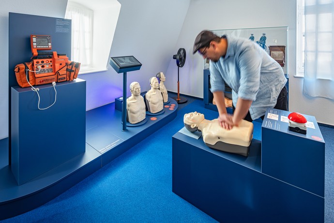 Ein Mann übt die Herzdruckmassage an einer Puppe in der Ausstellung der Villa Medica. Foto: Jannis Wiebusch
